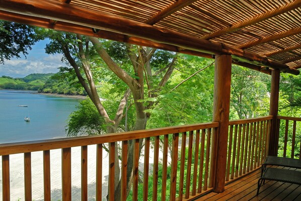 Una terraza de madera con vista a una playa y al mar.