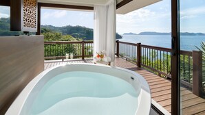 Un espace bien-être comprenant un bain à remous, une terrasse en bois et une vue panoramique sur un lac et des montagnes.