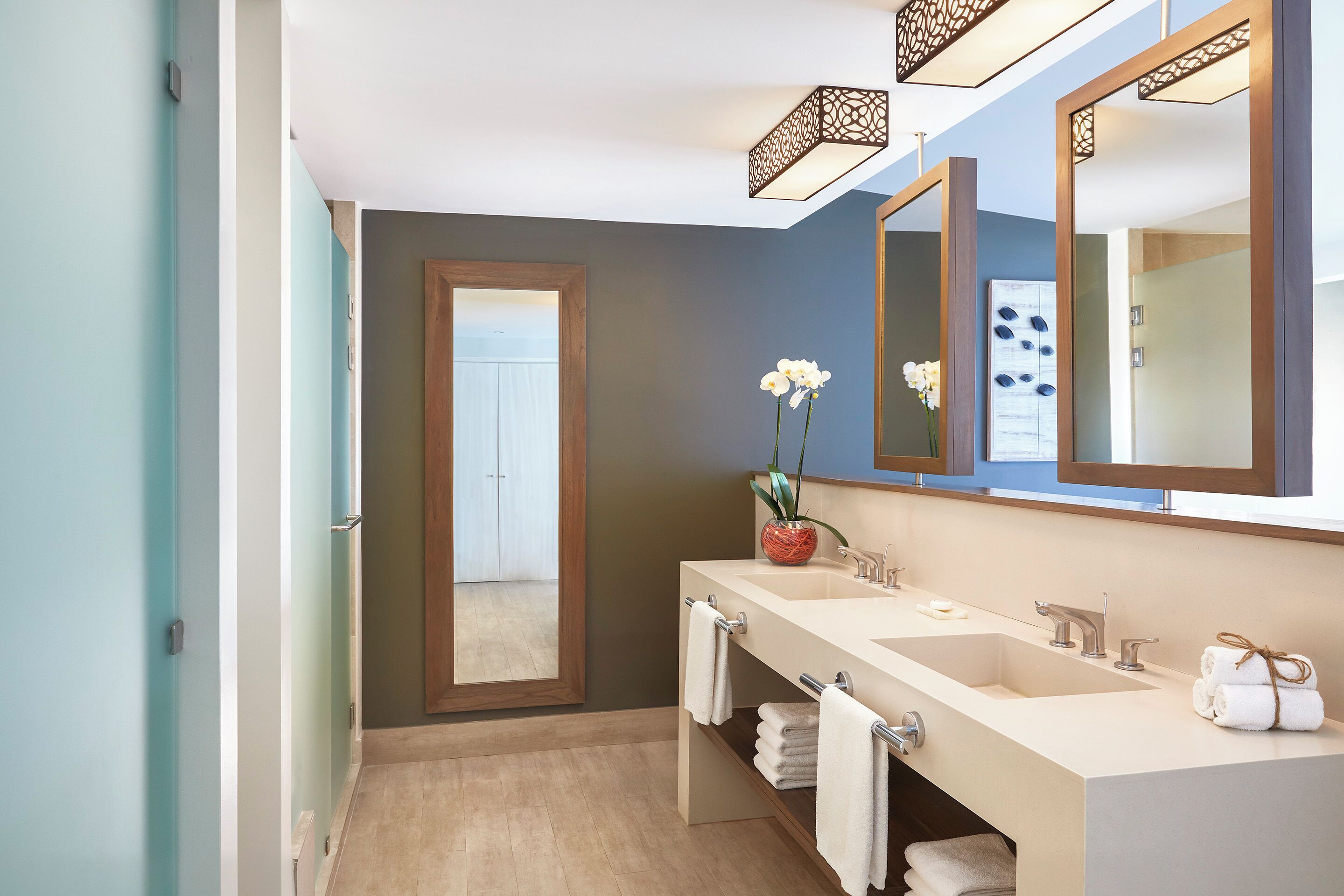 Un baño moderno con dos lavamanos, un espejo grande y una orquídea en maceta.