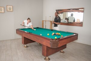 A pool table with balls, a mirror, and a framed picture on the wall.