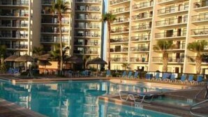 A hotel with multiple floors, a swimming pool, and lounge chairs. - Saida by South Padre Condo Rentals (South Padre Island)