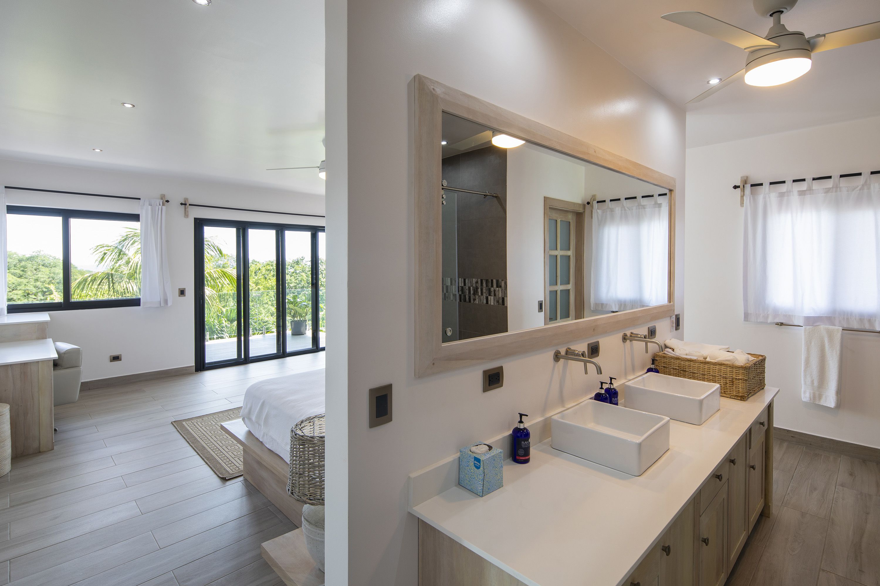 A modern bathroom with a large mirror, two sinks, and a shower.
