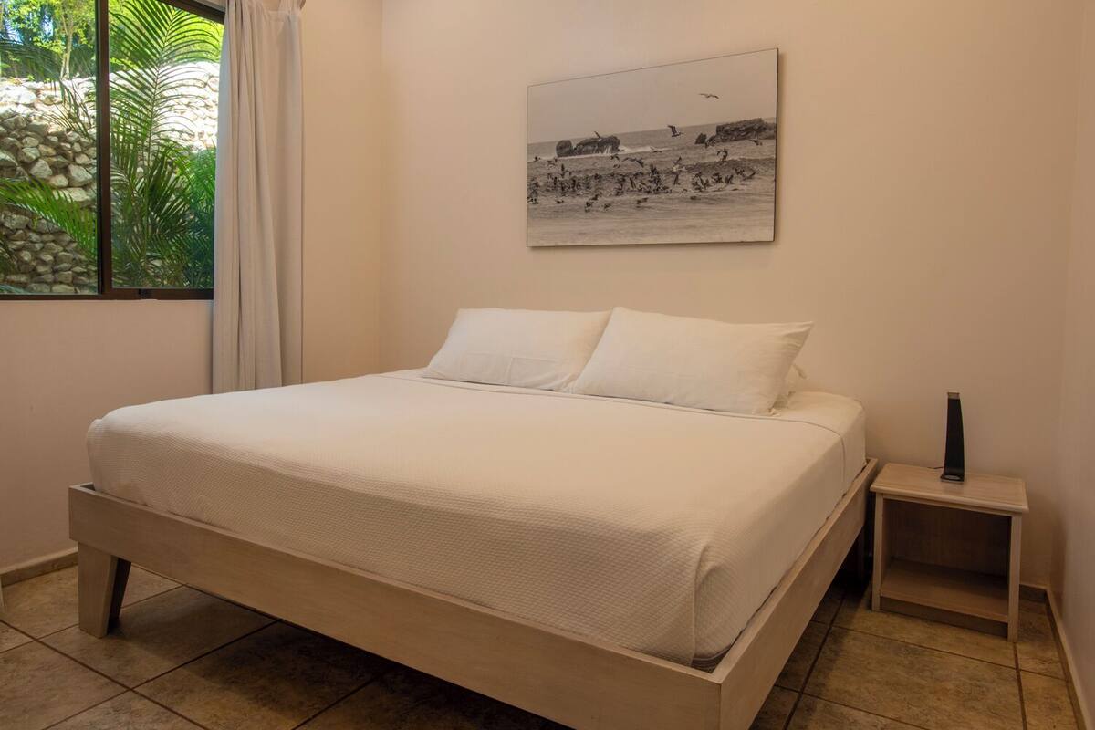 Un lit bien fait, avec du linge de lit blanc, dans une pièce dotée d’un mur en pierre et d’une fenêtre.