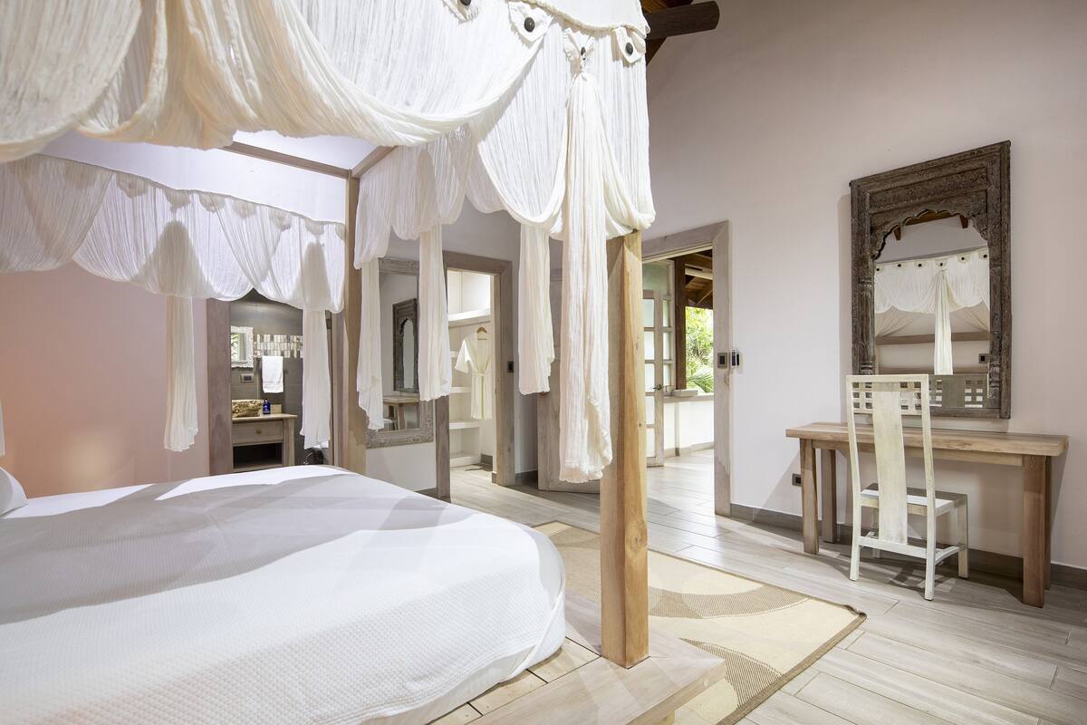 Une chambre à coucher avec un lit à baldaquin, un bureau en bois et un miroir.