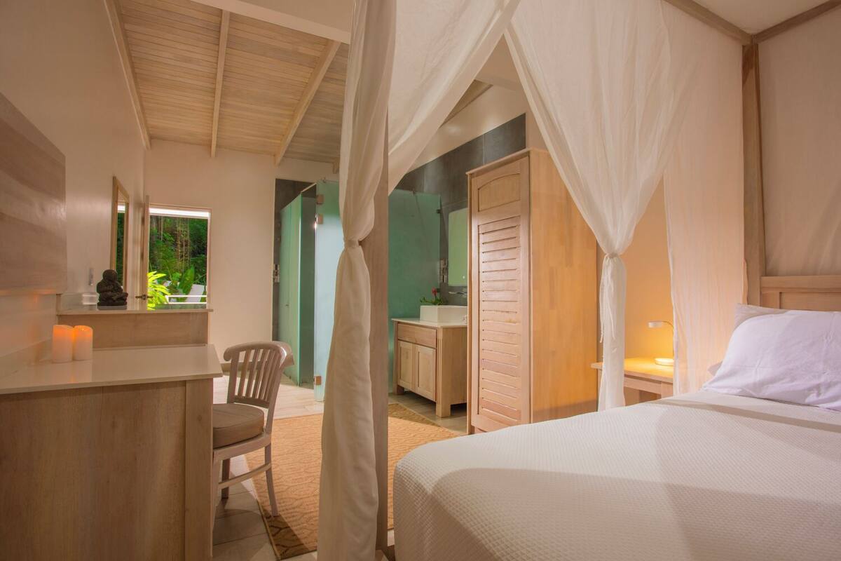 Une chambre à coucher avec un lit, un bureau, une chaise, un miroir et une fenêtre.