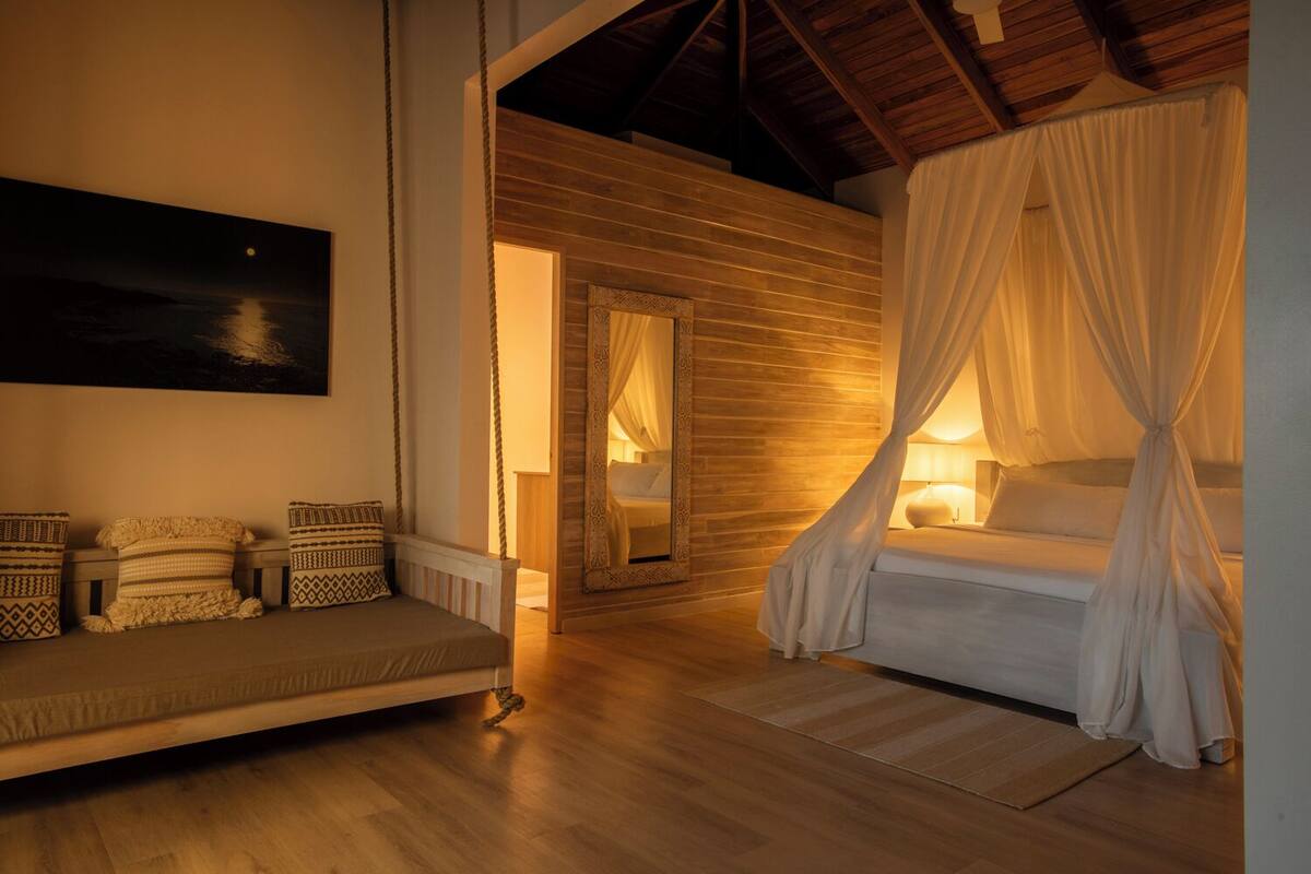 Une chambre à coucher avec un lit à baldaquin, un canapé et une vue sur le ciel étoilé.