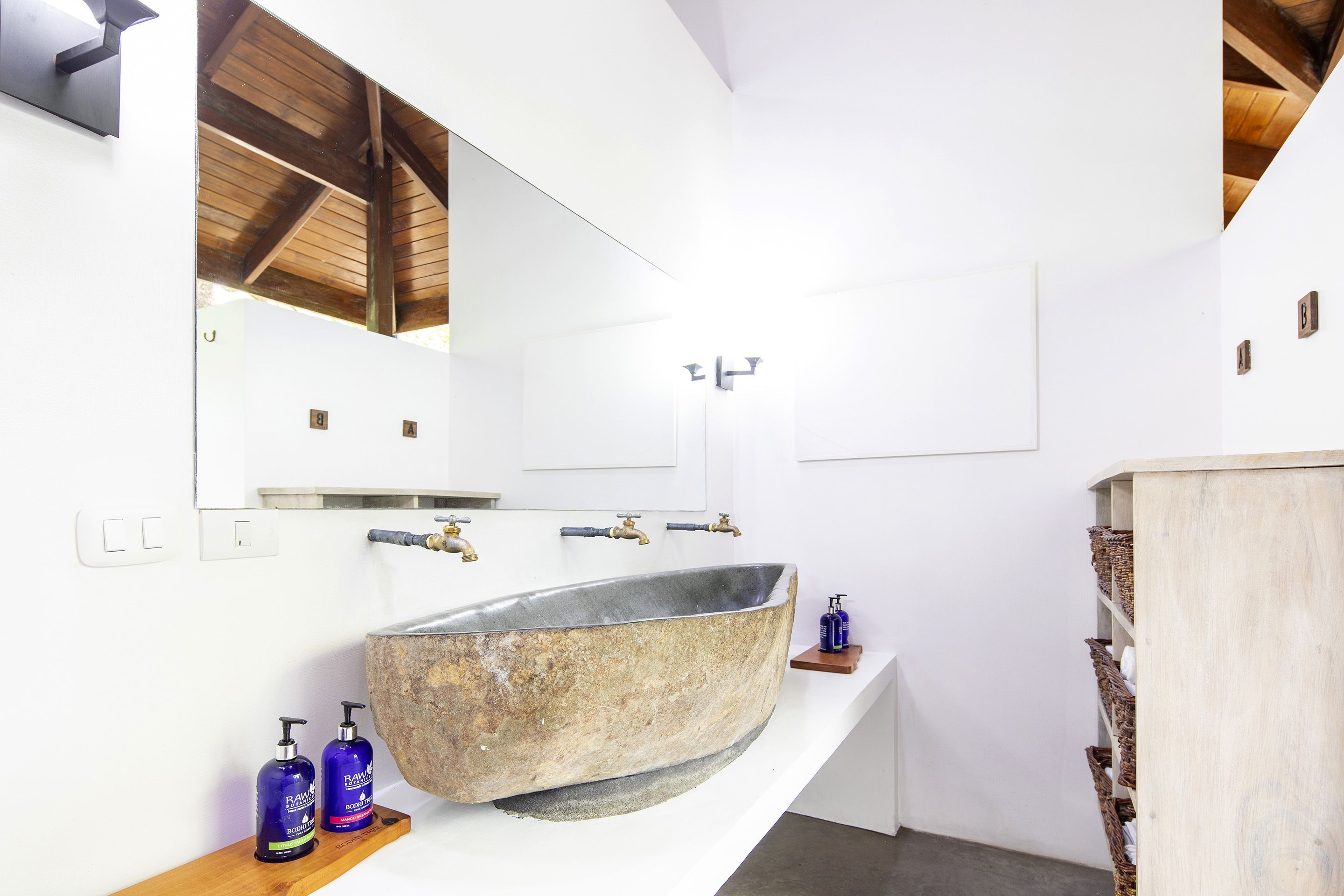 A bathroom with a large stone sink, wooden shelves, and a mirror.