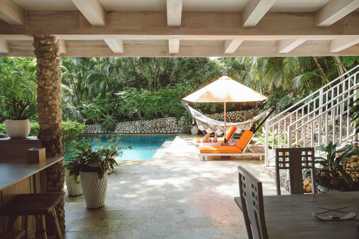 Un espace piscine équipé d’un hamac, de chaises longues et d’un escalier.
