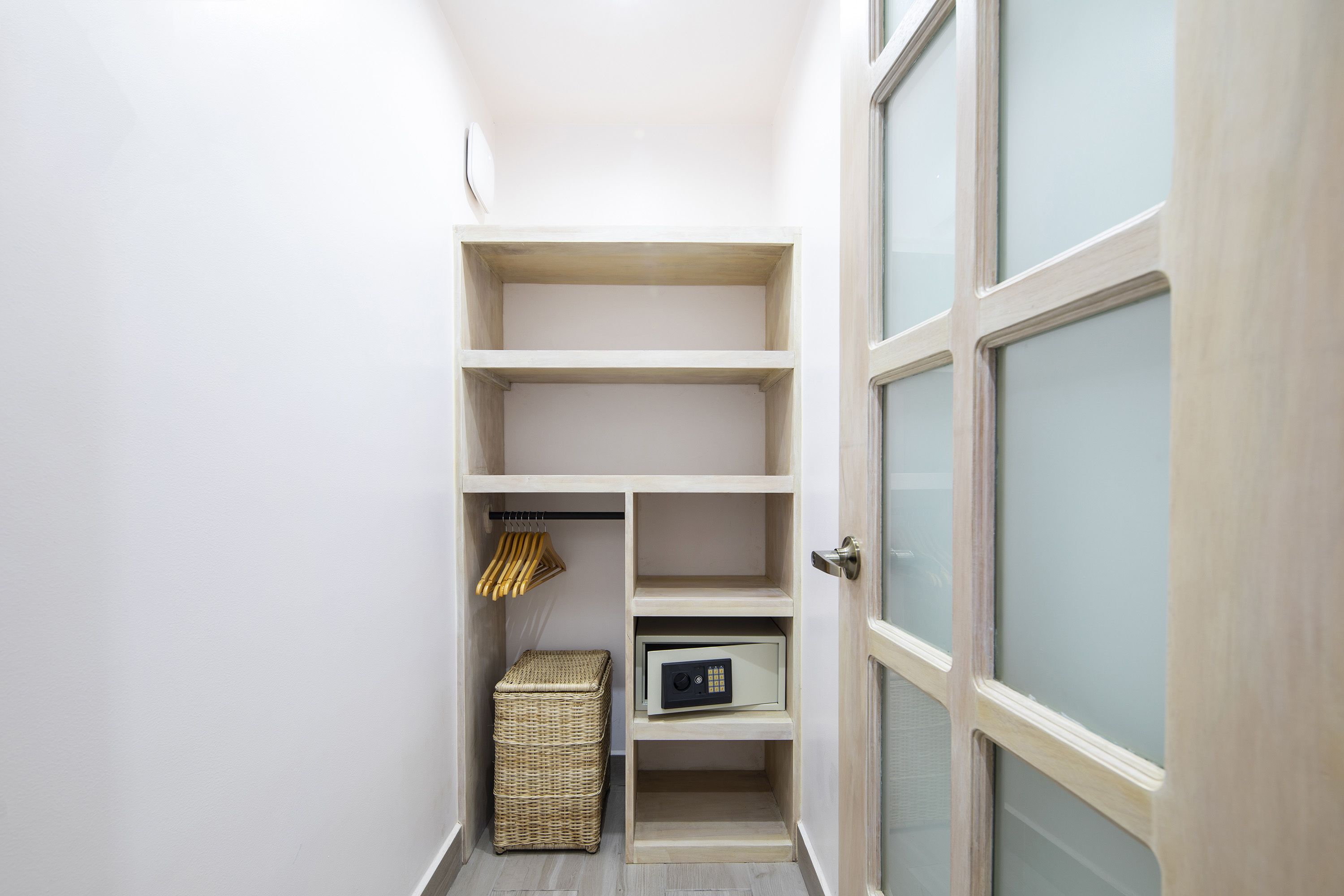 A narrow hallway with built-in shelving units, a wicker basket, and a secure storage box.