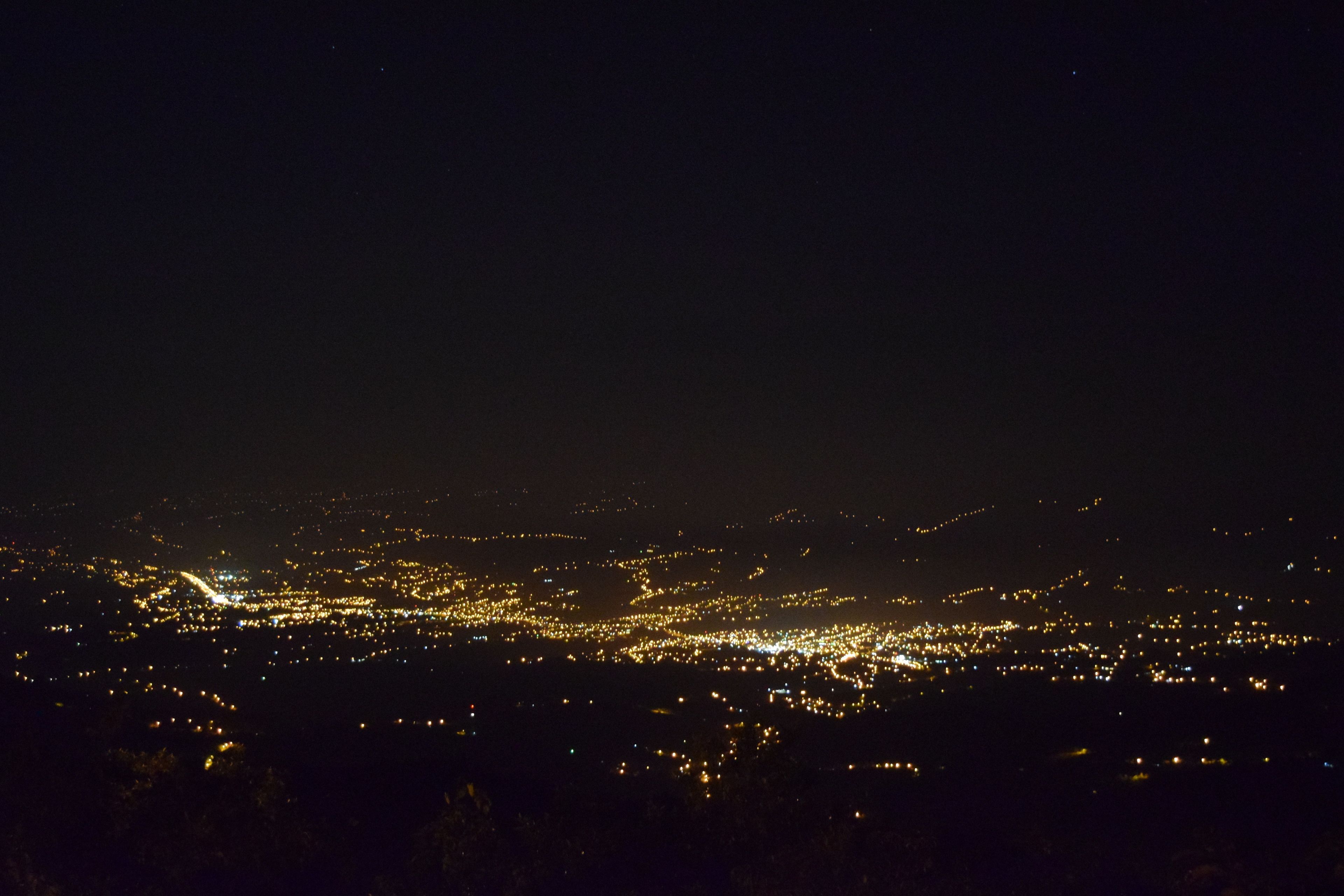 Un paisaje urbano nocturno con una gran concentración de luces, lo que indica una zona con mucha gente.
