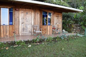 A rustic wooden cabin with numbered doors, a covered porch, and a garden area. - Mirador Valle del General (Páramo)