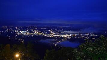 A nighttime cityscape with a view of the city lights and a distant mountain range.