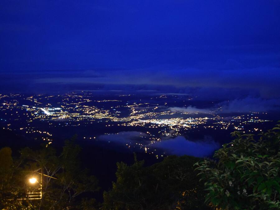 A nighttime cityscape with a view of the city lights and a distant mountain range.