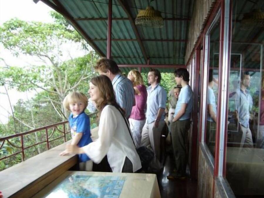 A group of people standing on a covered outdoor area with a table in the foreground displaying a map.