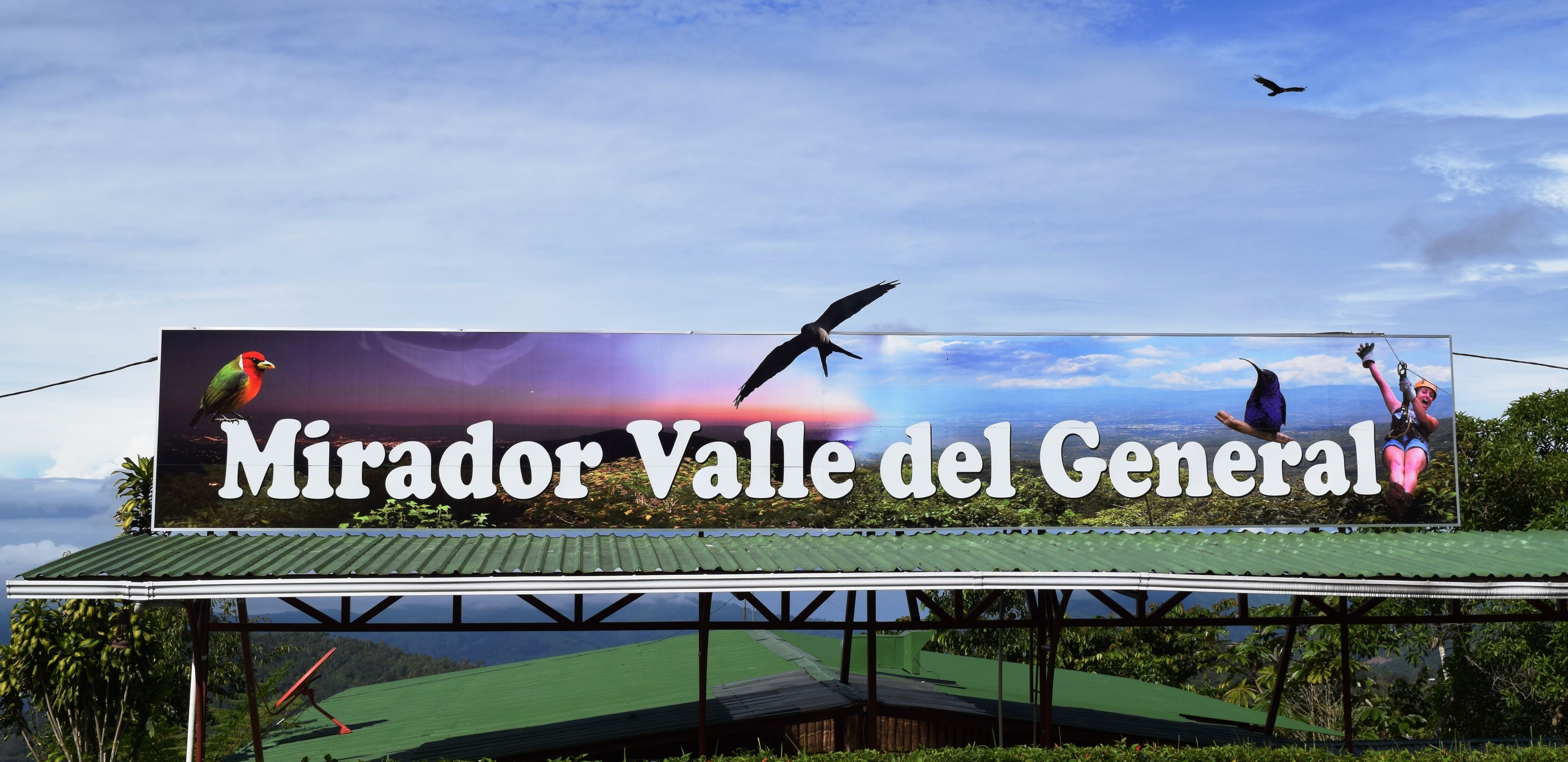 A billboard advertising 'Mirador Valle del General' with a scenic view of a valley and a bird in flight.
