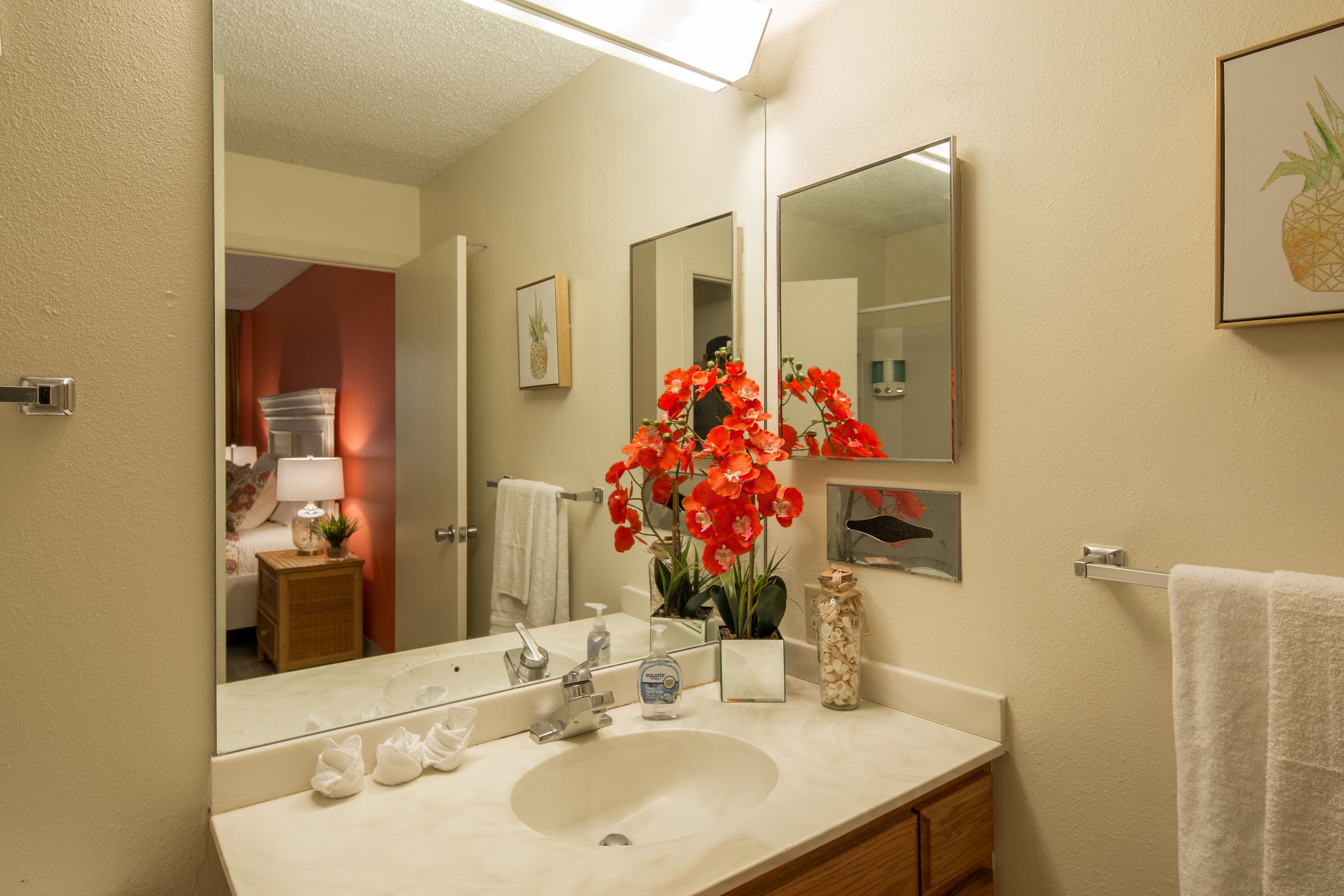 A bathroom with a large mirror, a sink, and a towel rack.