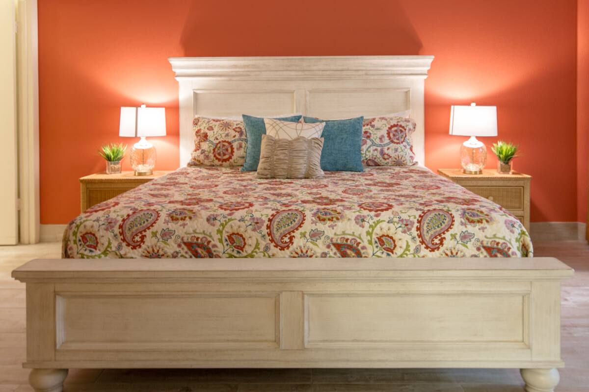 A bed with a floral patterned bedspread, two nightstands with lamps, and a white headboard.