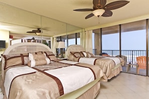 A hotel room with two beds, a balcony with a view, ceiling fans, and a large mirror. - Sea Vista by South Padre Condo Rentals (South Padre Island)