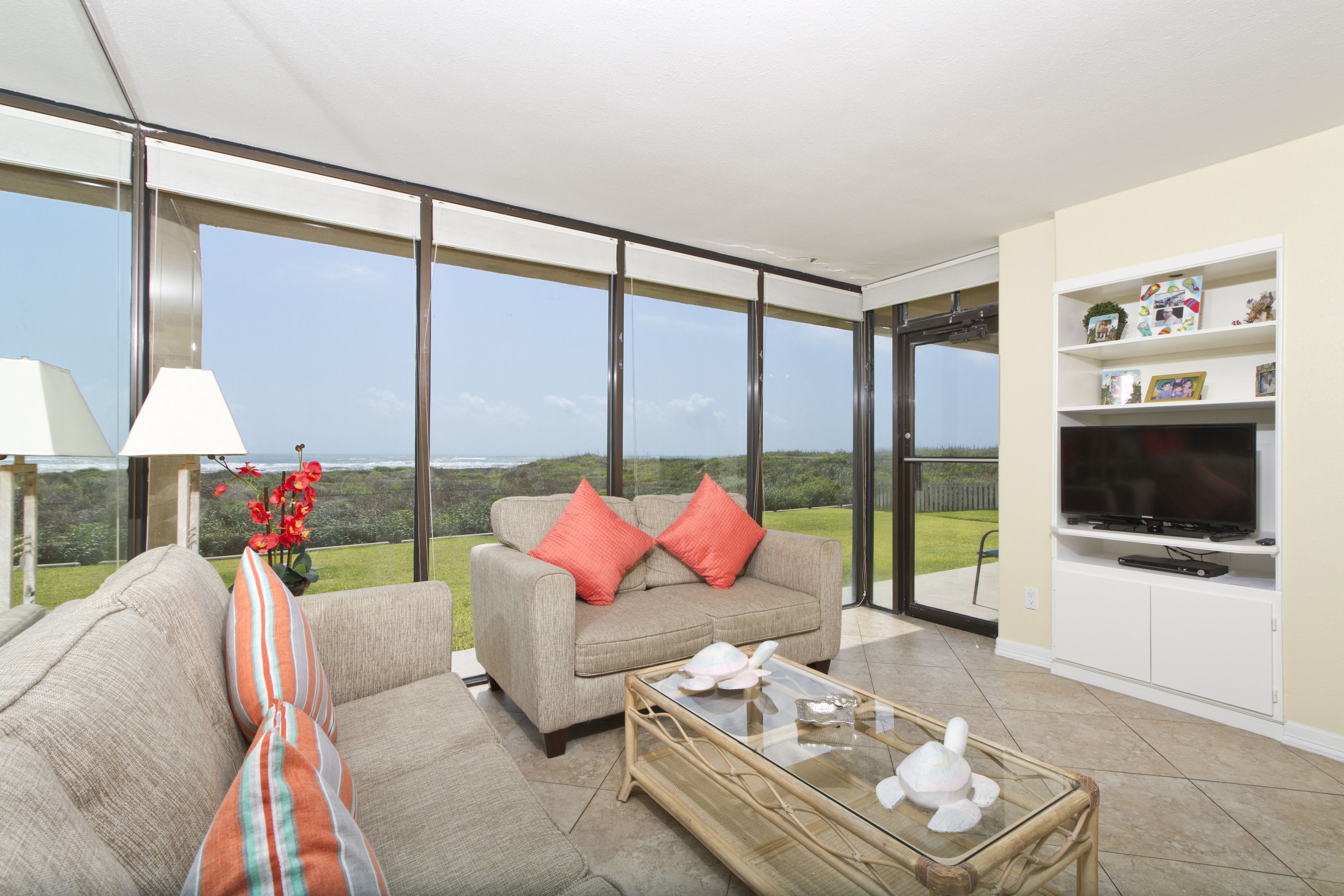 A spacious living room with a large window, a sofa, a coffee table, and a TV.