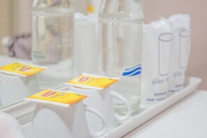 Uno scaffale con tazze bianche e una bottiglia d'acqua.