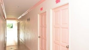 Un pasillo con puertas rosadas y un letrero con un número sobre una puerta.