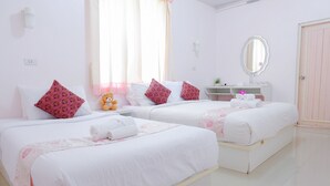 Habitación de hotel con dos camas, cada una con ropa de cama blanca y almohadas estampadas de color rosa. Hay una mesita con un espejo y un estante con artículos de aseo.