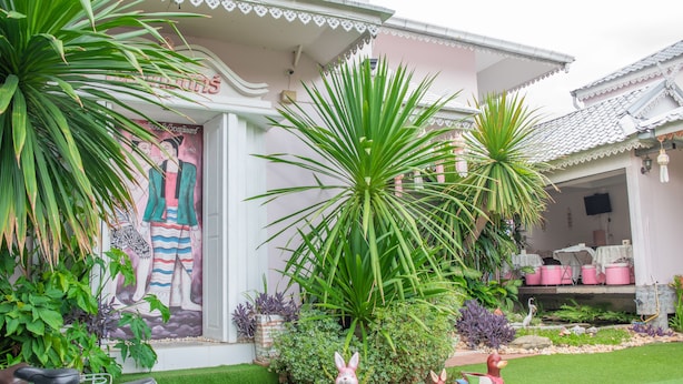 Una casa con un mural, un jardín con diversas plantas y un tejado de tejas.