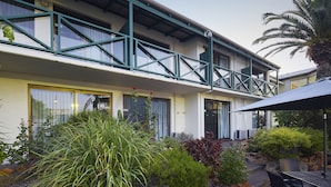 A hotel with a balcony, outdoor seating, and a landscaped garden.