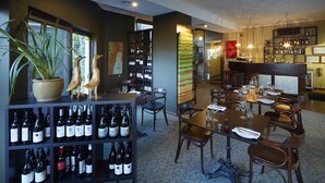 A restaurant with a bar area, wine shelves, and a dining table set for four.