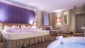 Ein Hotelzimmer mit Bett, Sofa, einem kleinen Tisch, einer Badewanne und einem Spiegel.