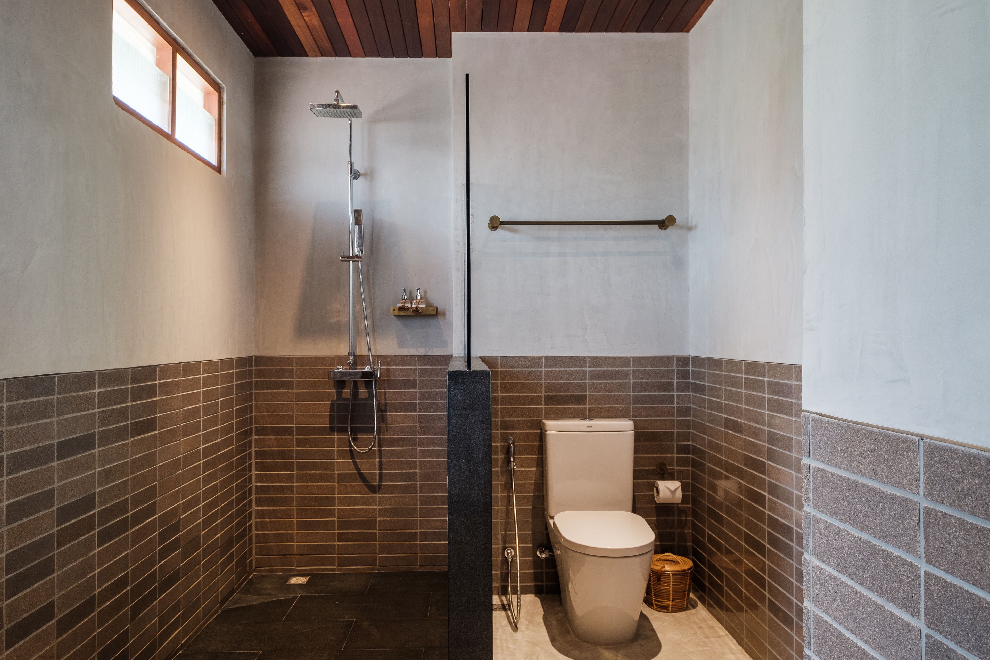 A modern bathroom with a shower, toilet, and a towel rack.