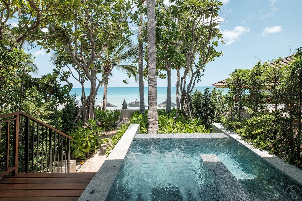 A pool area with a wooden deck and a view of the ocean.