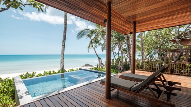 Eine Holzterrasse mit Pool, Liegestühlen und Blick auf den Ozean.