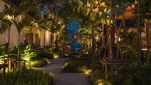 Ein Gartenweg bei Nacht, der zu einem Gebäude mit Blick auf das Meer führt.