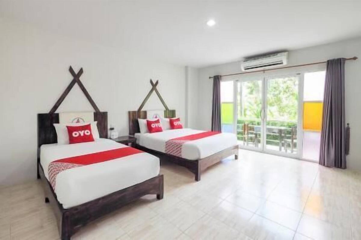 A hotel room with two beds, a balcony, and an air conditioning unit.