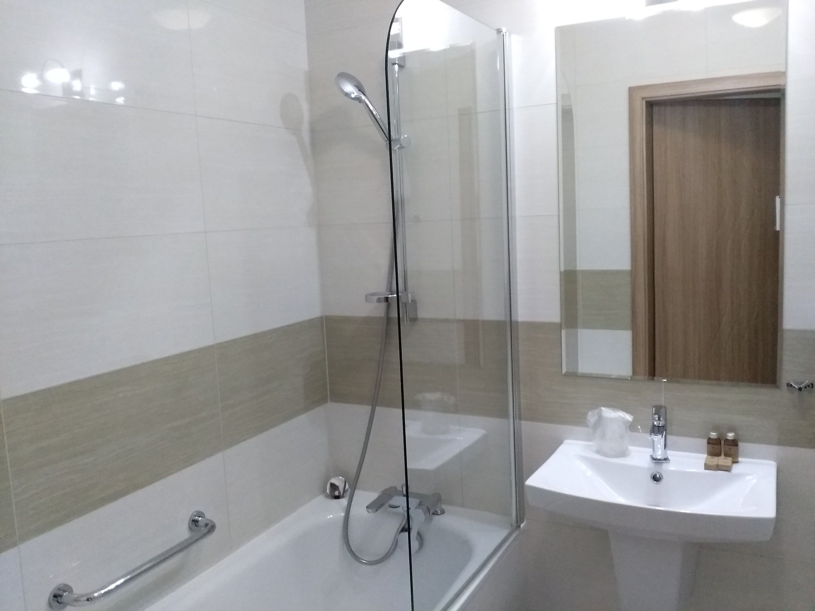 A modern bathroom with a glass-enclosed shower, a bathtub, and a sink.