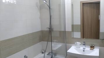 A modern bathroom with a glass-enclosed shower, a bathtub, and a sink.