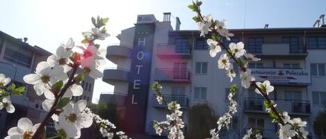 A hotel with a prominent 'HOTEL' sign, a restaurant named 'Poleczka', and a clear view of the surrounding area.