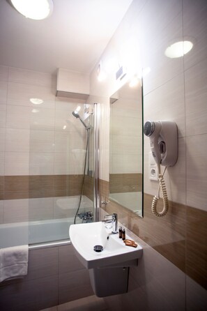 A modern bathroom with a glass shower enclosure, a white sink, and a hairdryer mounted on the wall. - POLECZKI RESIDENCE APARTMENTS  (Warsaw)