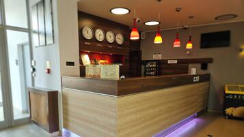 A reception desk with a wooden finish, multiple clocks on the wall, and pendant lighting.