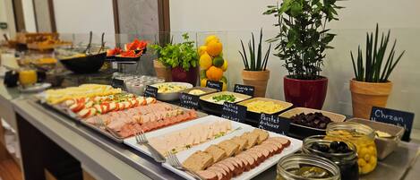 A buffet with various food options and labels, including meats, cheeses, and fruits.