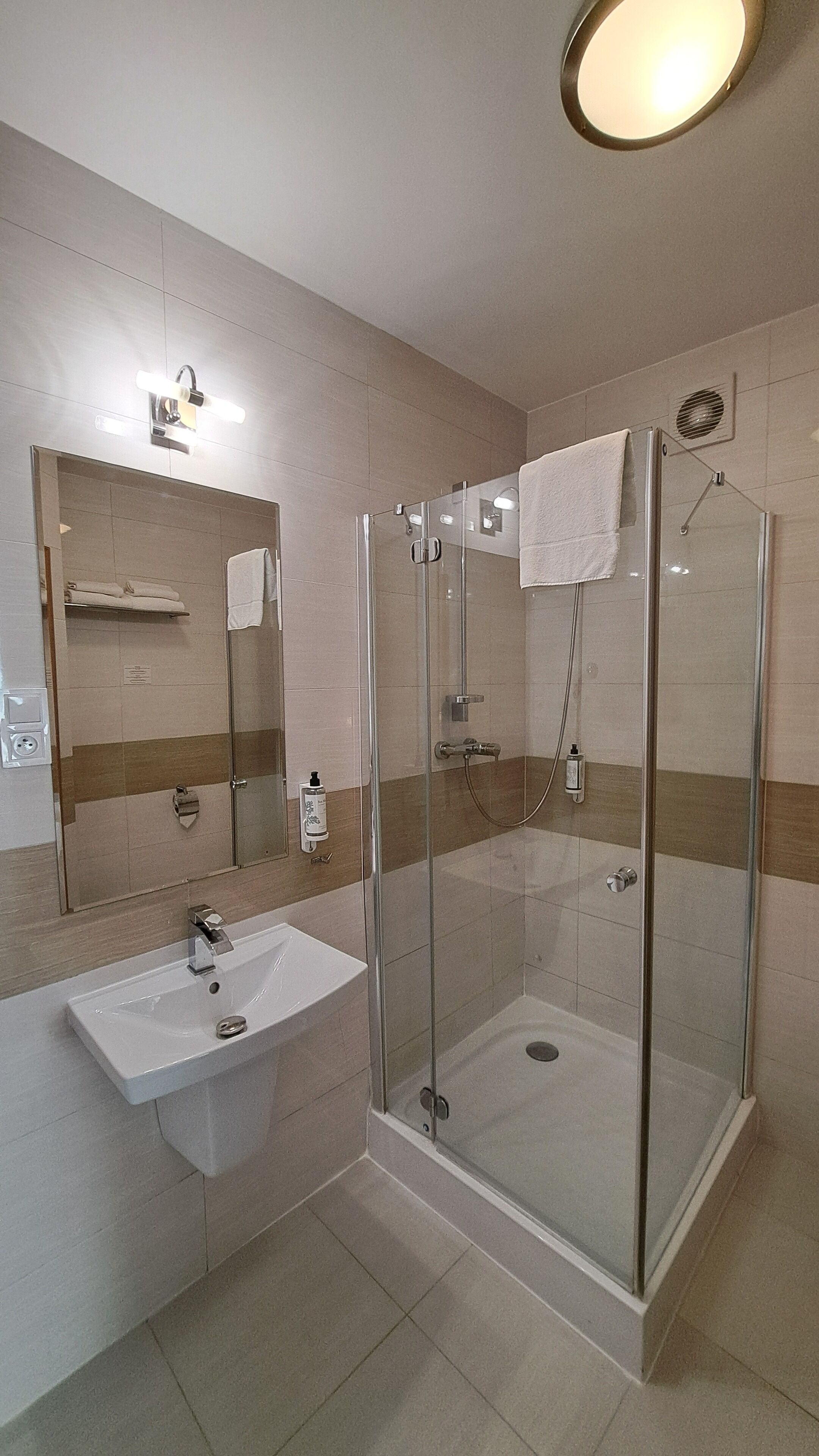 A modern bathroom with a glass-enclosed shower, a sink, and a mirror above the mirror.