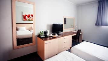 Een hotelkamer met een bed, een bureau met een computer, een televisie en een spiegel.
