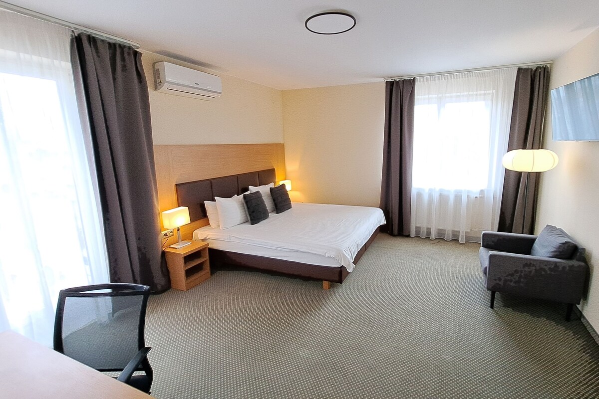 Hotellihuone, jossa on sänky, työpöytä, tuoli, televisio ja ilmastointilaite.