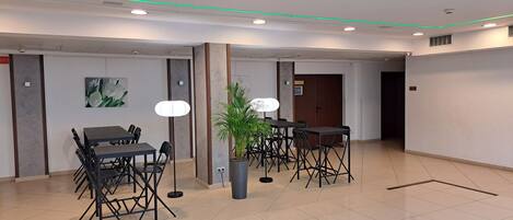 A spacious room with a large table and chairs, a potted plant, and a door.