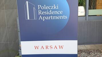Cartell de Poleczi Residence Apartments a Varsòvia, amb una icona de l'edifici i el nom del lloc.