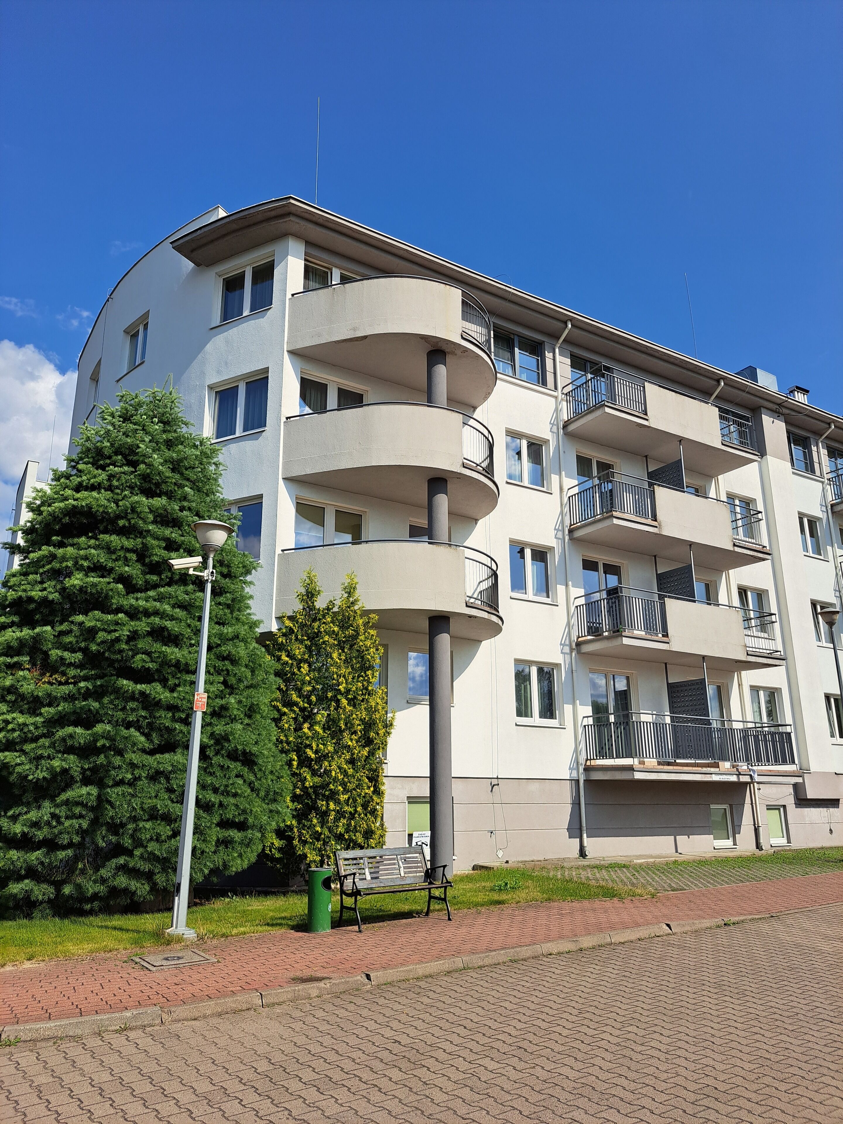 Ein mehrstöckiges Wohngebäude mit Balkonen, einer Straßenlaterne und einer Bank.