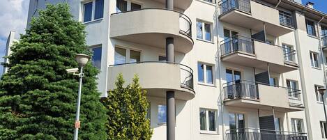 Un edificio residencial de varios pisos con balcones, una farola y un banco.