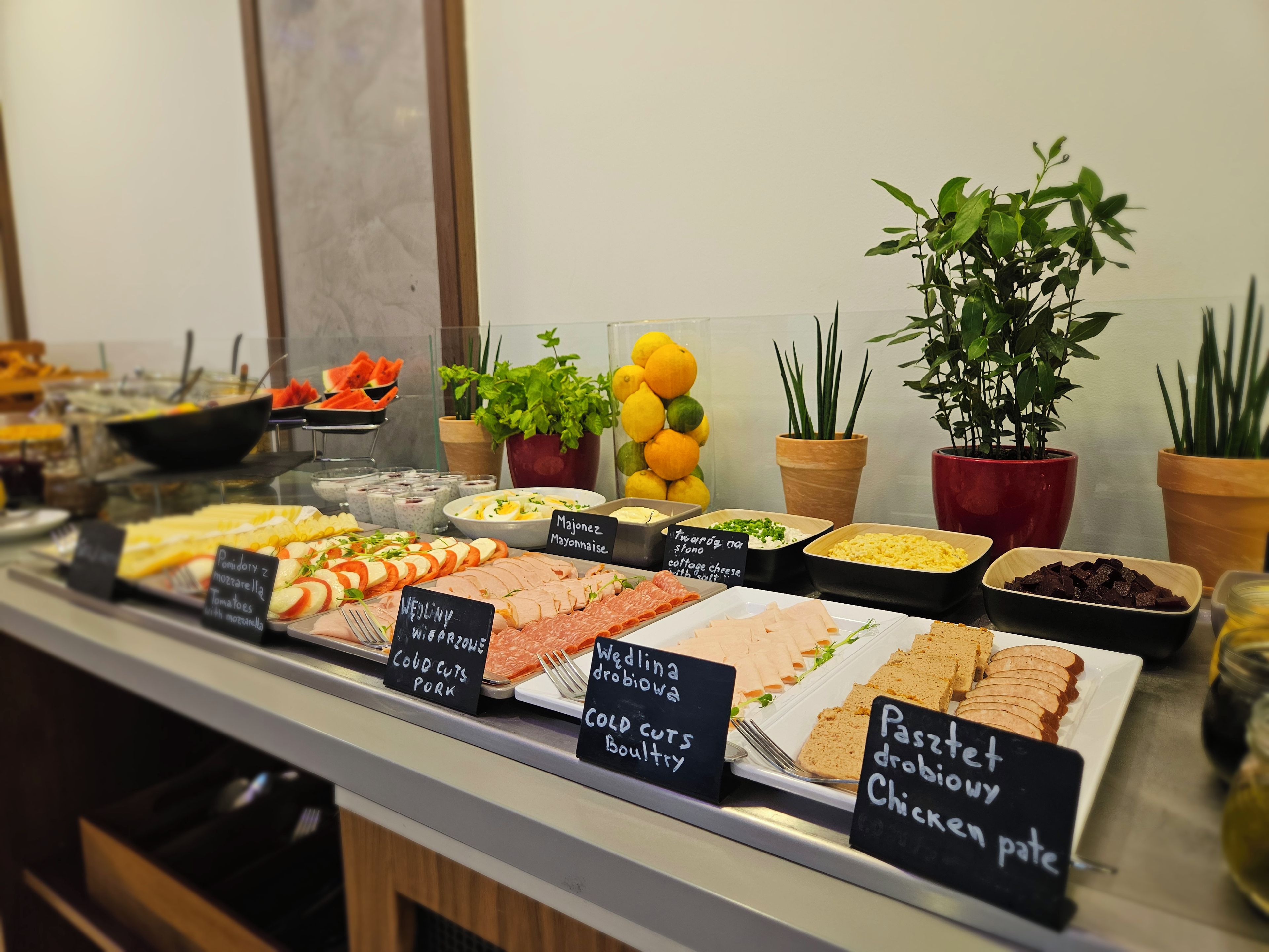 A buffet with various food options including cold cuts, cheese, and pastries.