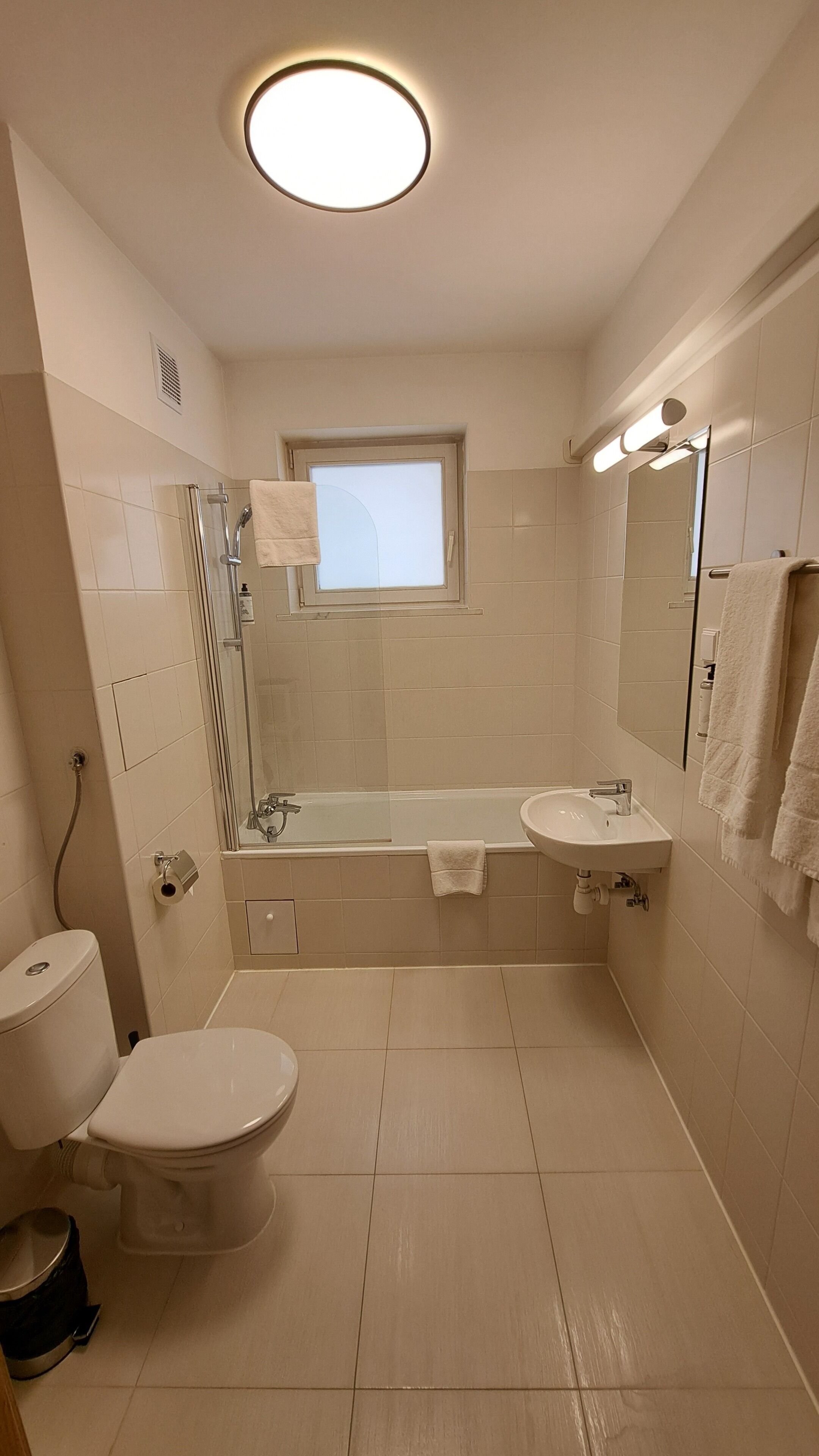 Een moderne badkamer met toilet, een glazen douche, een badkuip en een wastafel.